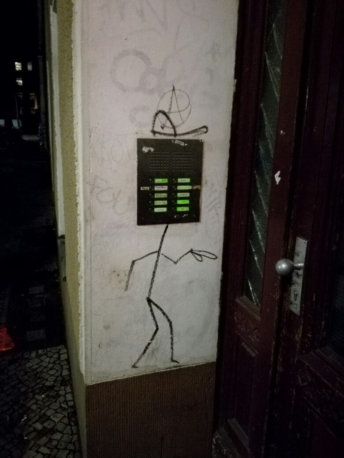Photo of a street art showing door bell signs with a drawing that looks like a man