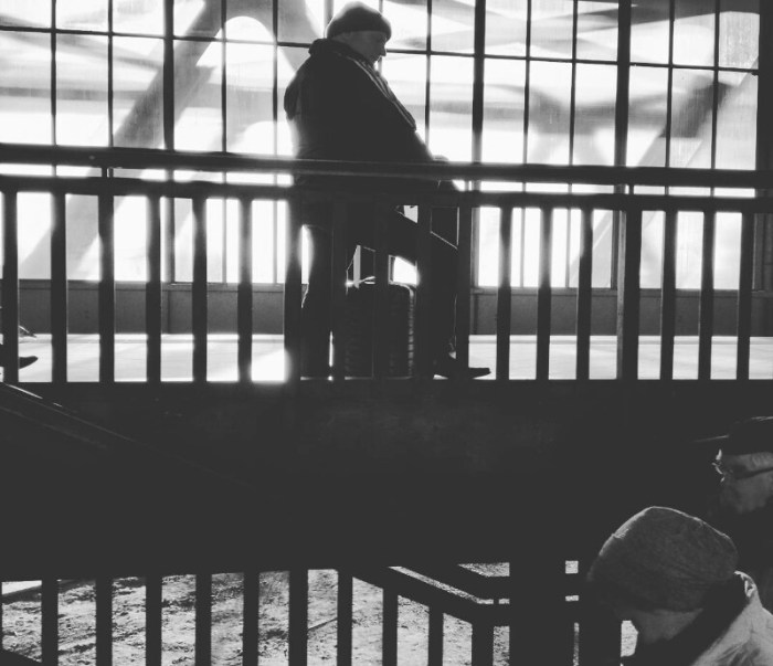 Black and white street photo of a man waiting at train station Schöneberg, Berlin