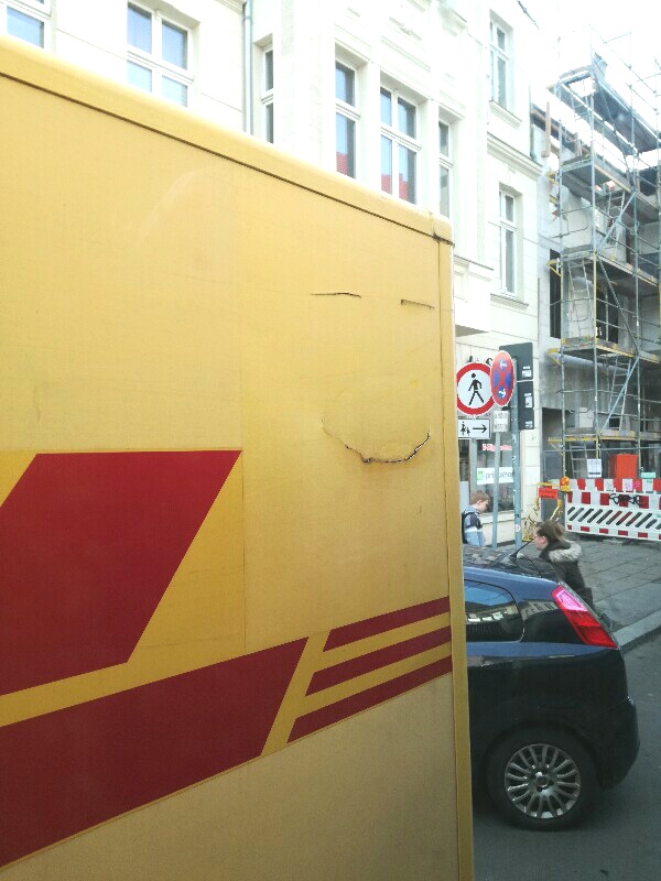 Holes on a DHL truck that look like a smiling face. A photo by Stefan Klenke